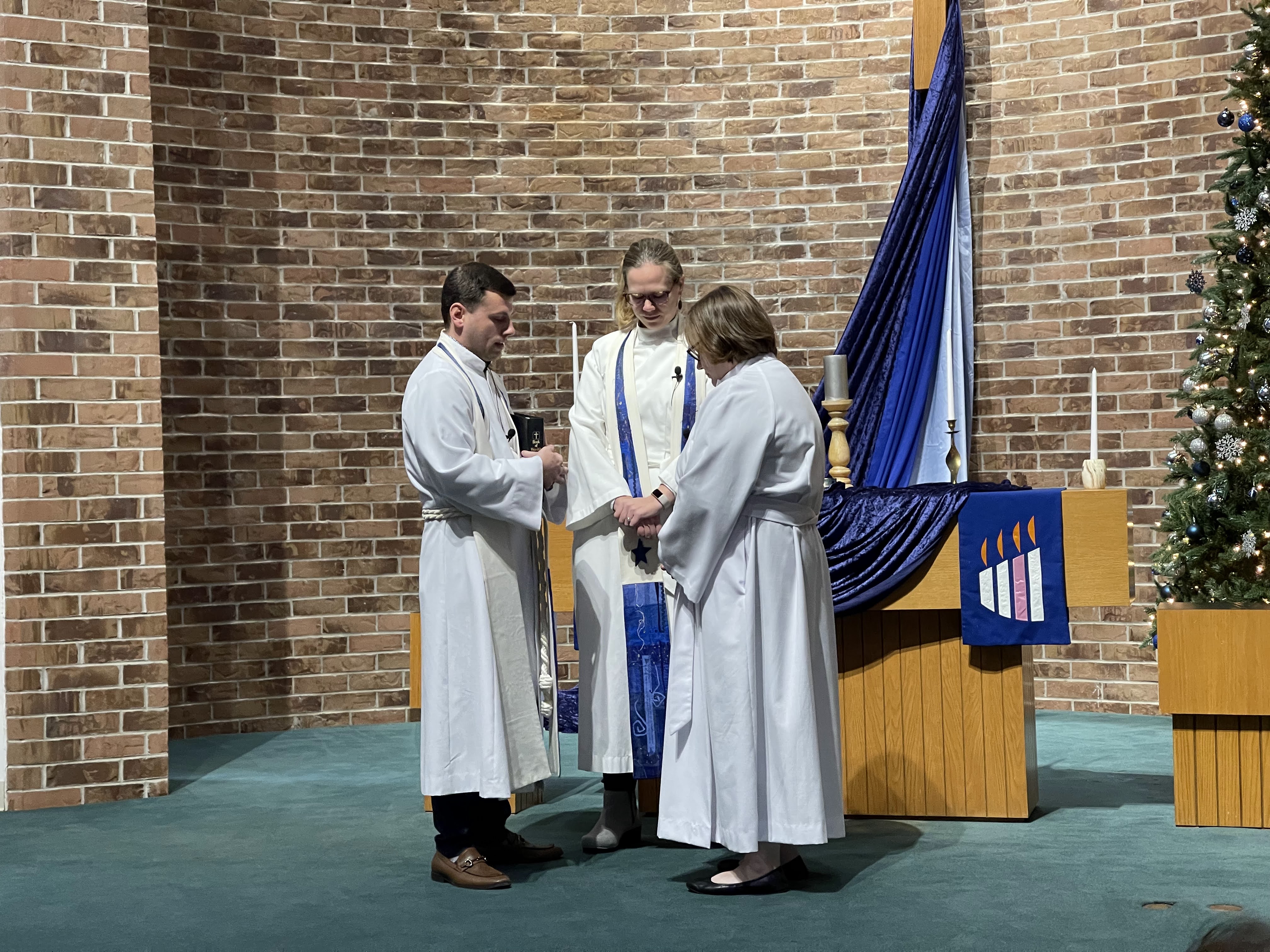 Three pastors in prayer Three pastors in pastoral robes facing each other in prayer